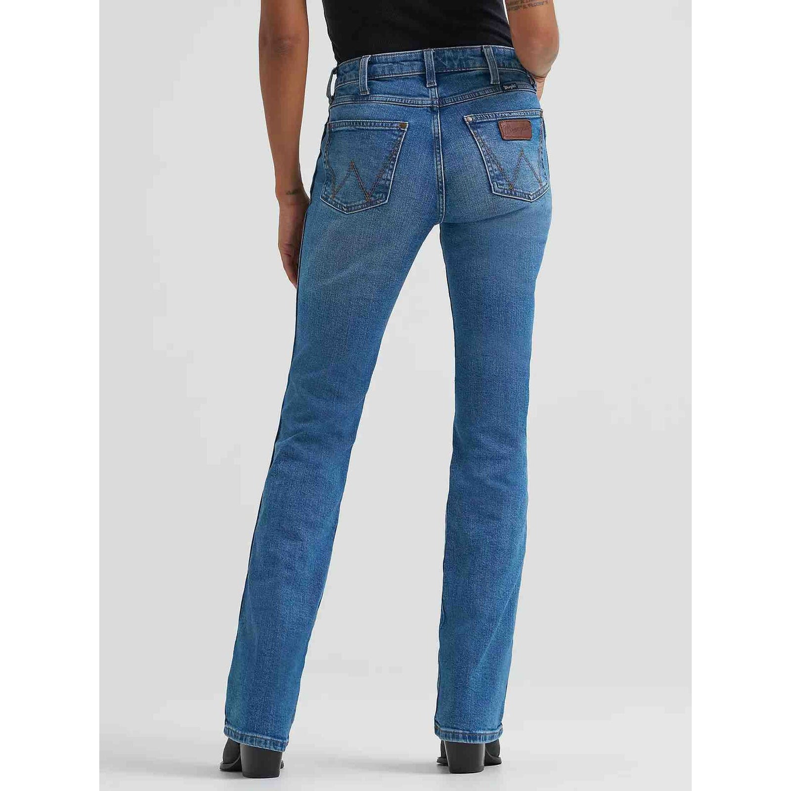Back view of Women's Wrangler Retro Bailey High Rise Bootcut Jean in blue denim with stitched back pockets.