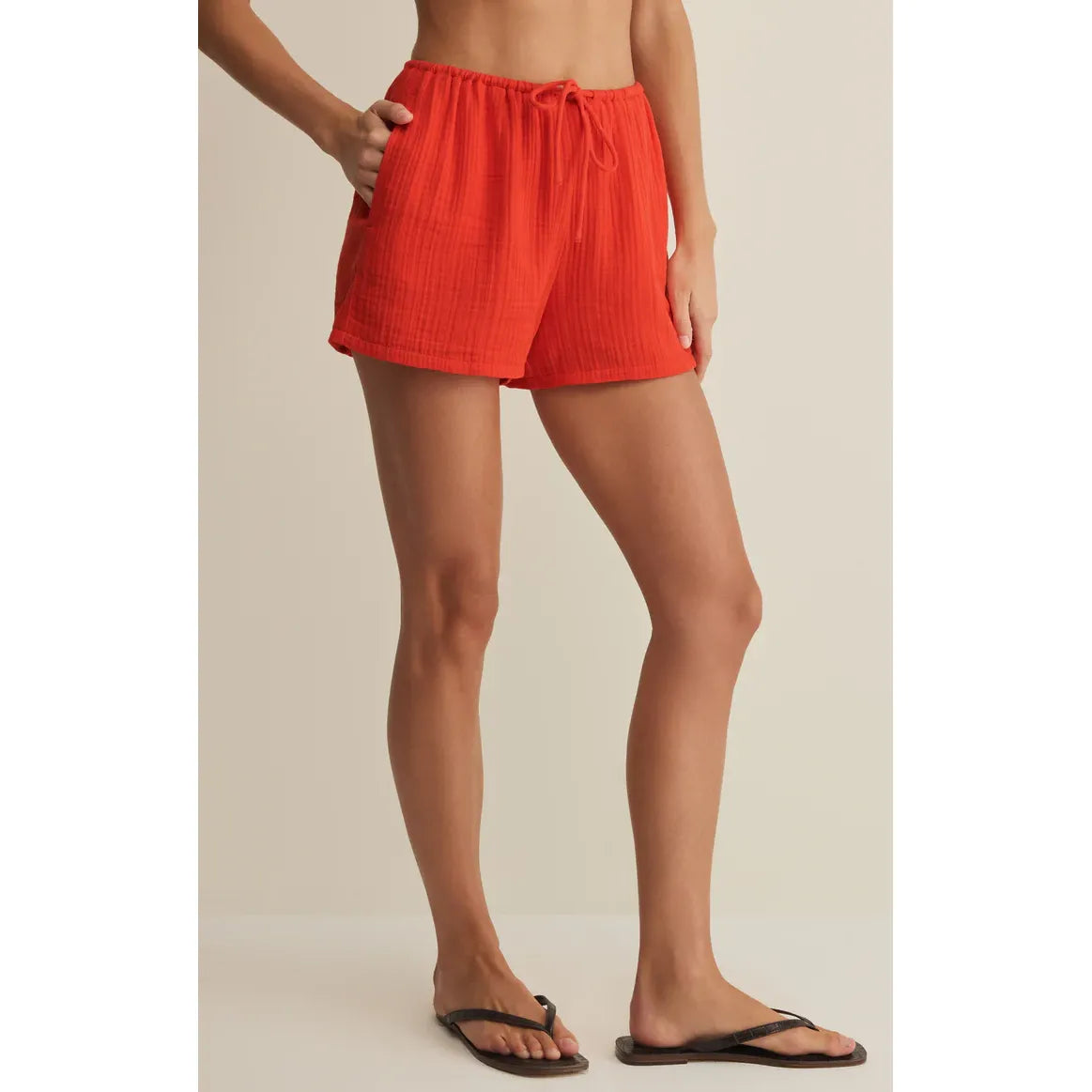Model in red Z Supply Daylight Airy Shorts with drawstring waist and side pockets.