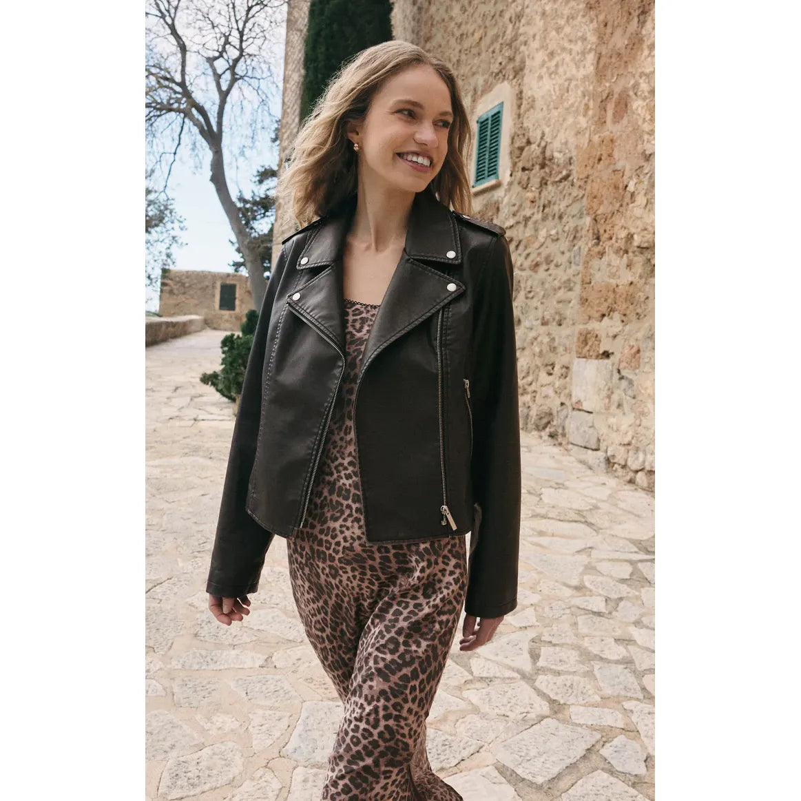 Z Supply Alchemy Faux Leather Moto Jacket worn by a model in a leopard print outfit outdoors.