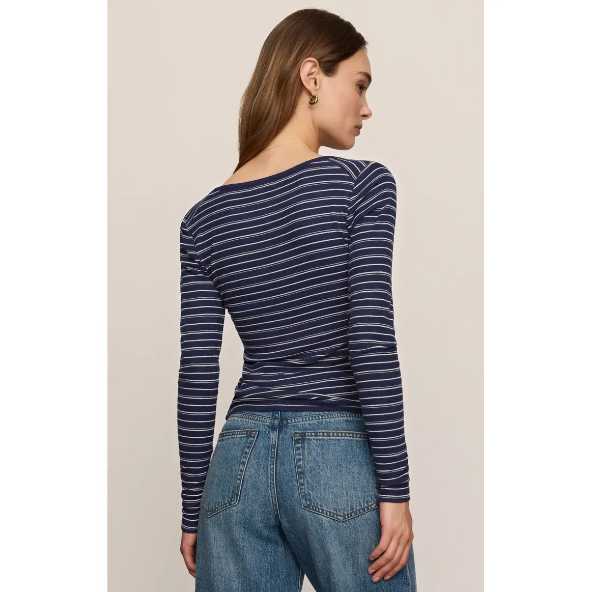 Back view of a fitted navy and white striped long-sleeve henley top with a scooped neckline, paired with blue jeans.