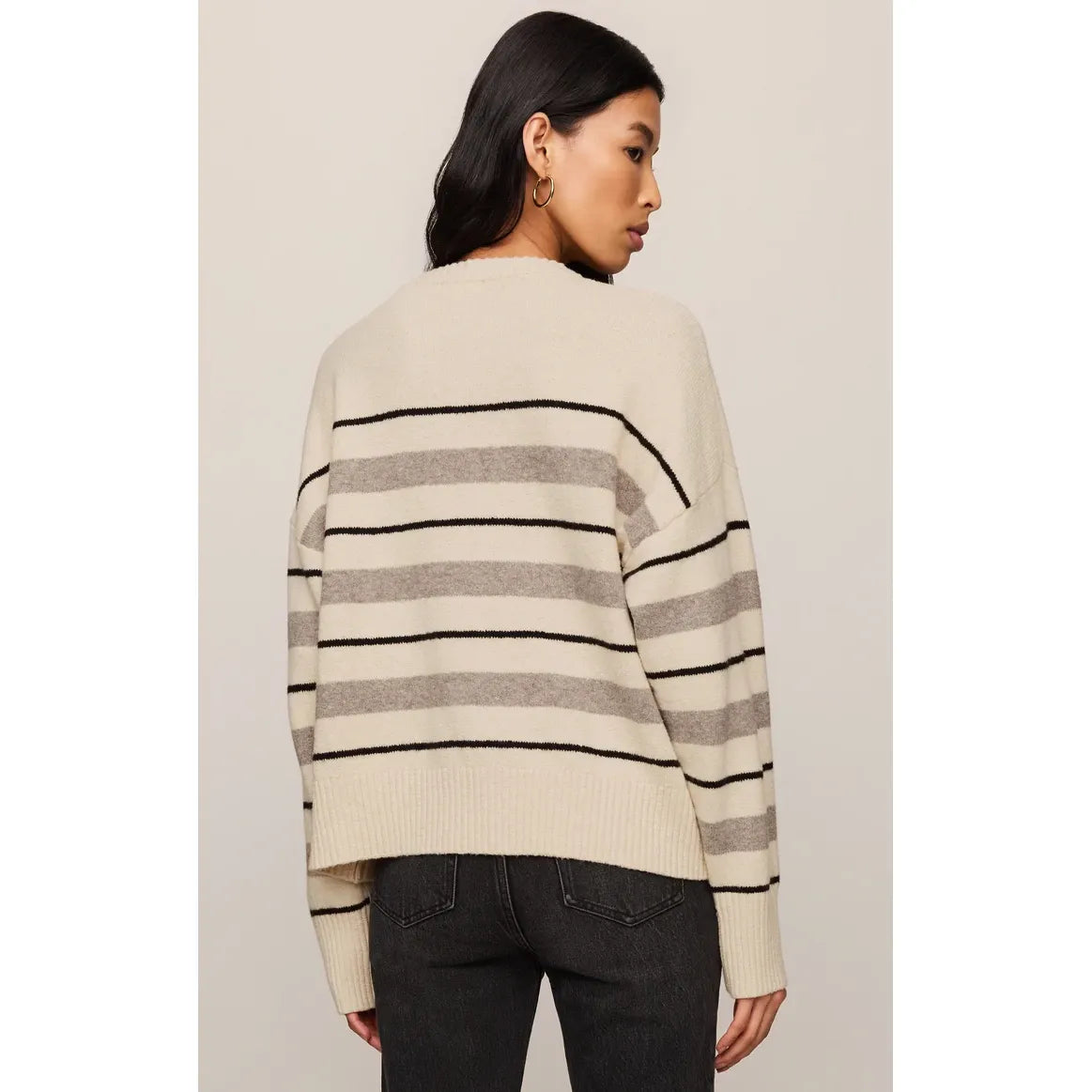 Back view of a woman wearing a cream Z Supply Cirrus striped sweater with grey and black horizontal bands in a relaxed fit.