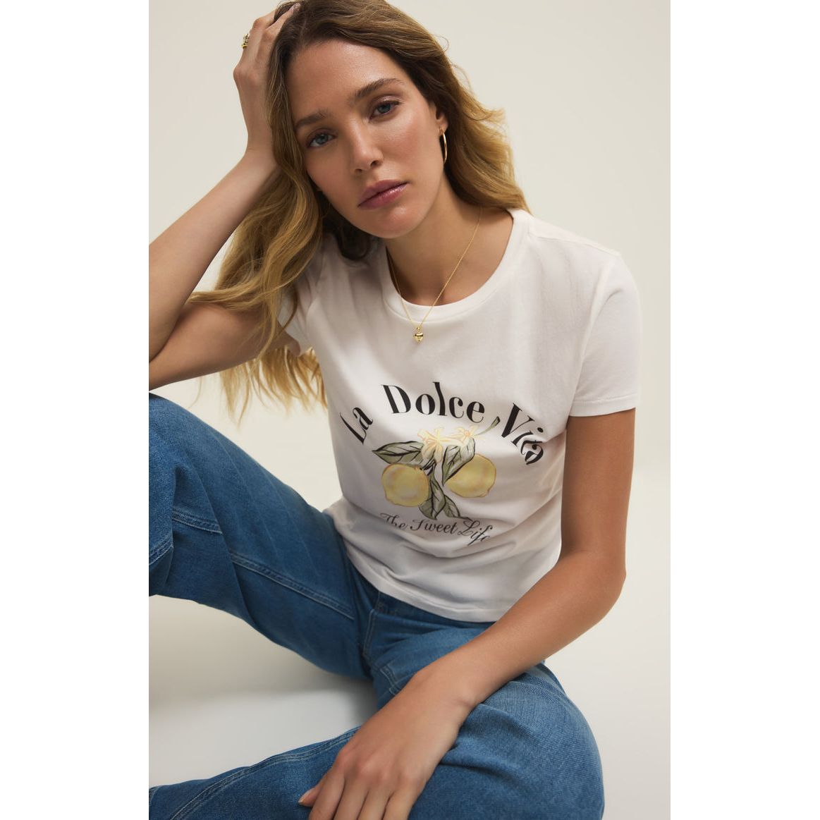 Woman wearing White Z Supply Dolce Tourist Tee with lemon motif and retro typography, relaxed fit.