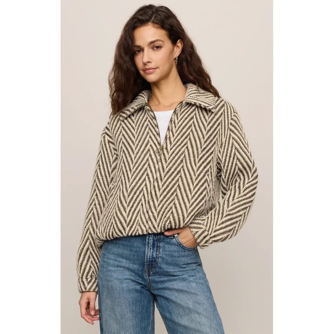 Woman wearing a beige and brown herringbone bubble jacket with antique brass zip, snap cuffs, and vintage-inspired texture paired with blue jeans.