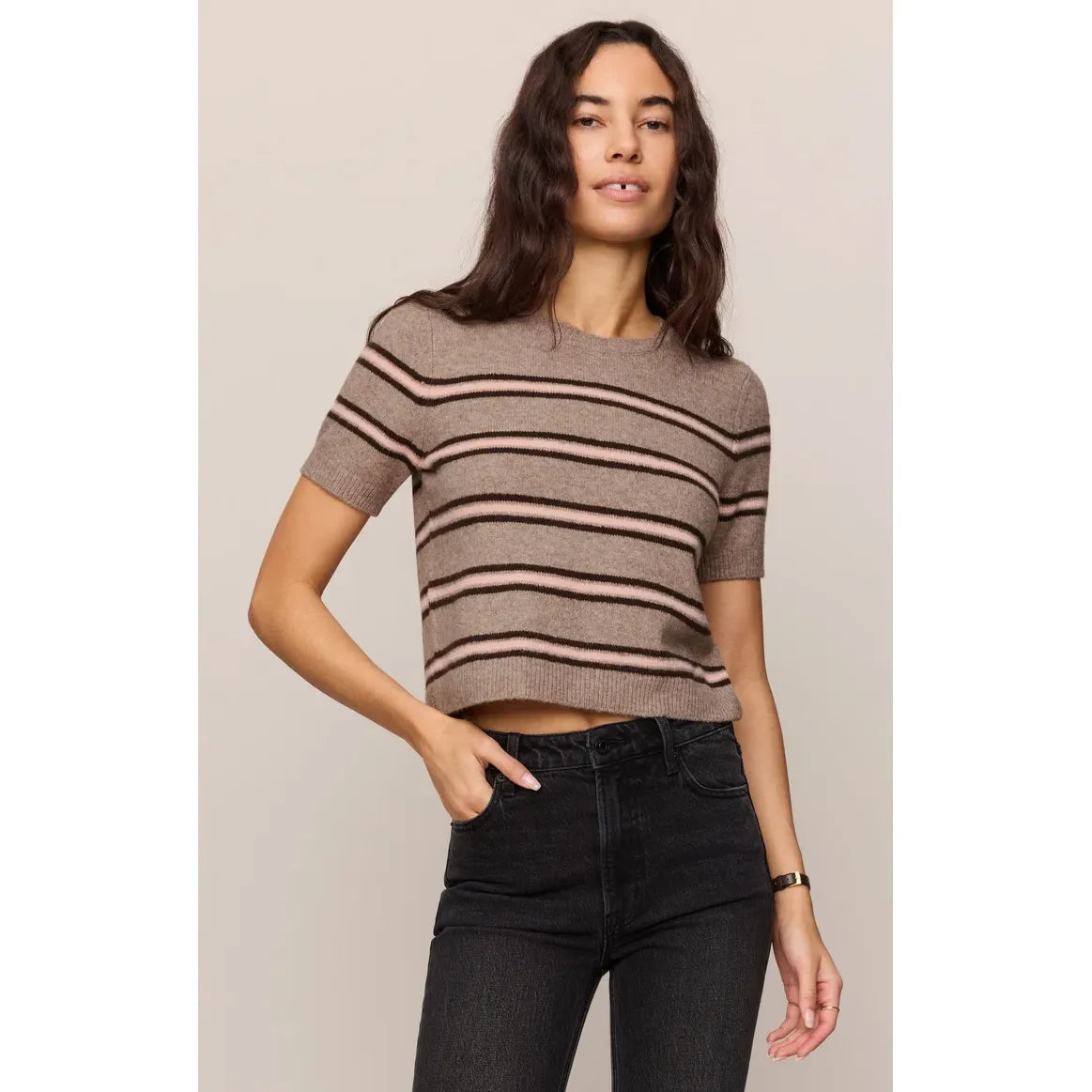Striped short-sleeve sweater tee in taupe with pink and black horizontal stripes, paired with dark jeans for a casual look.