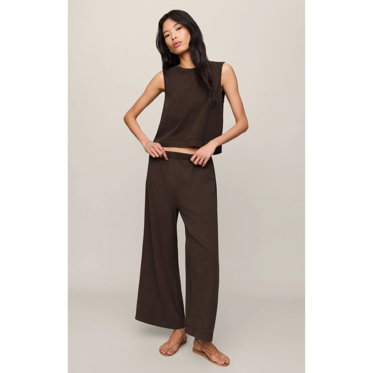 Model wearing brown Z Supply Scout Jersey Crop Flare Pant, high-rise, ankle-length, elastic waist, cotton jersey.