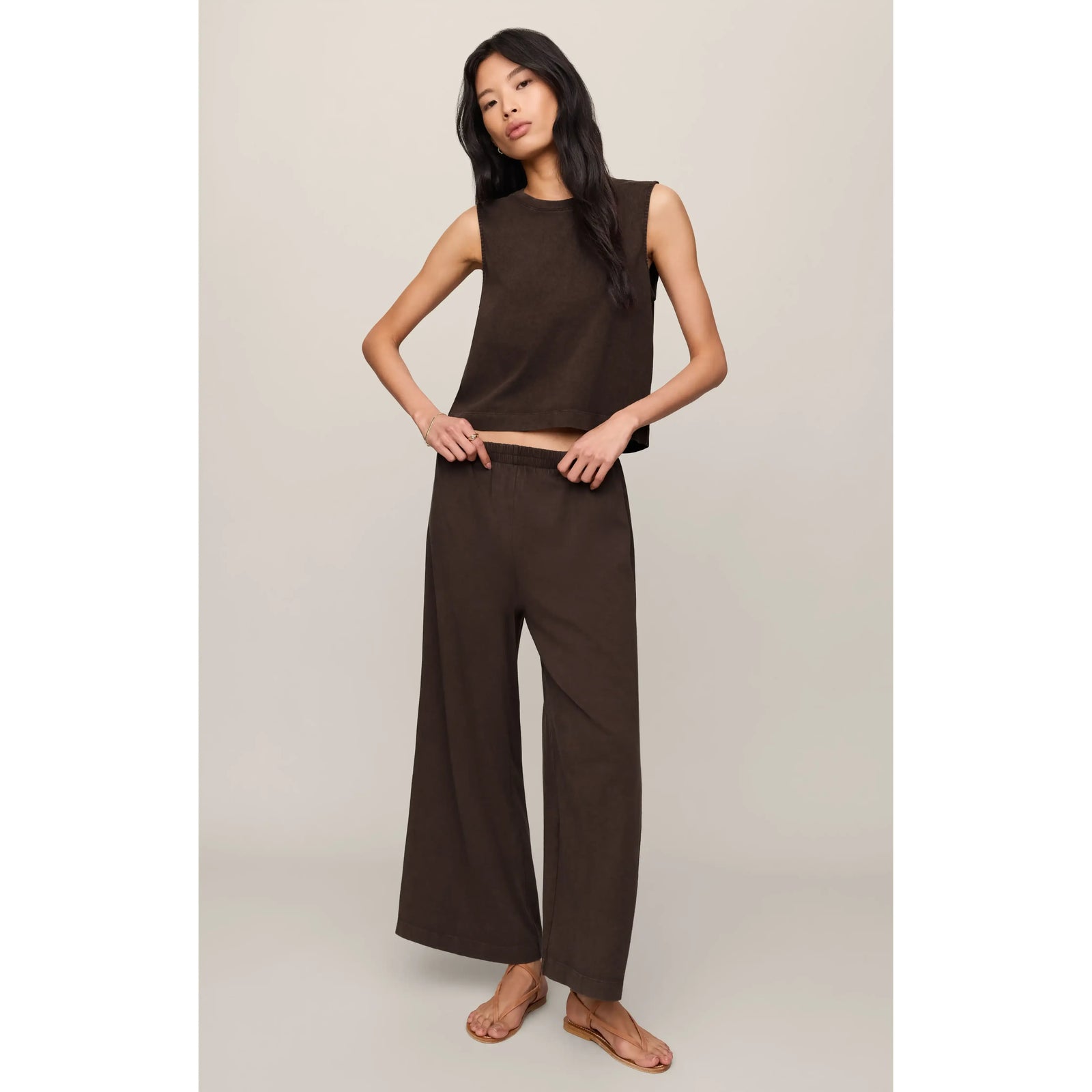 Model wearing brown Z Supply Scout Jersey Crop Flare Pant, high-rise, ankle-length, elastic waist, cotton jersey.