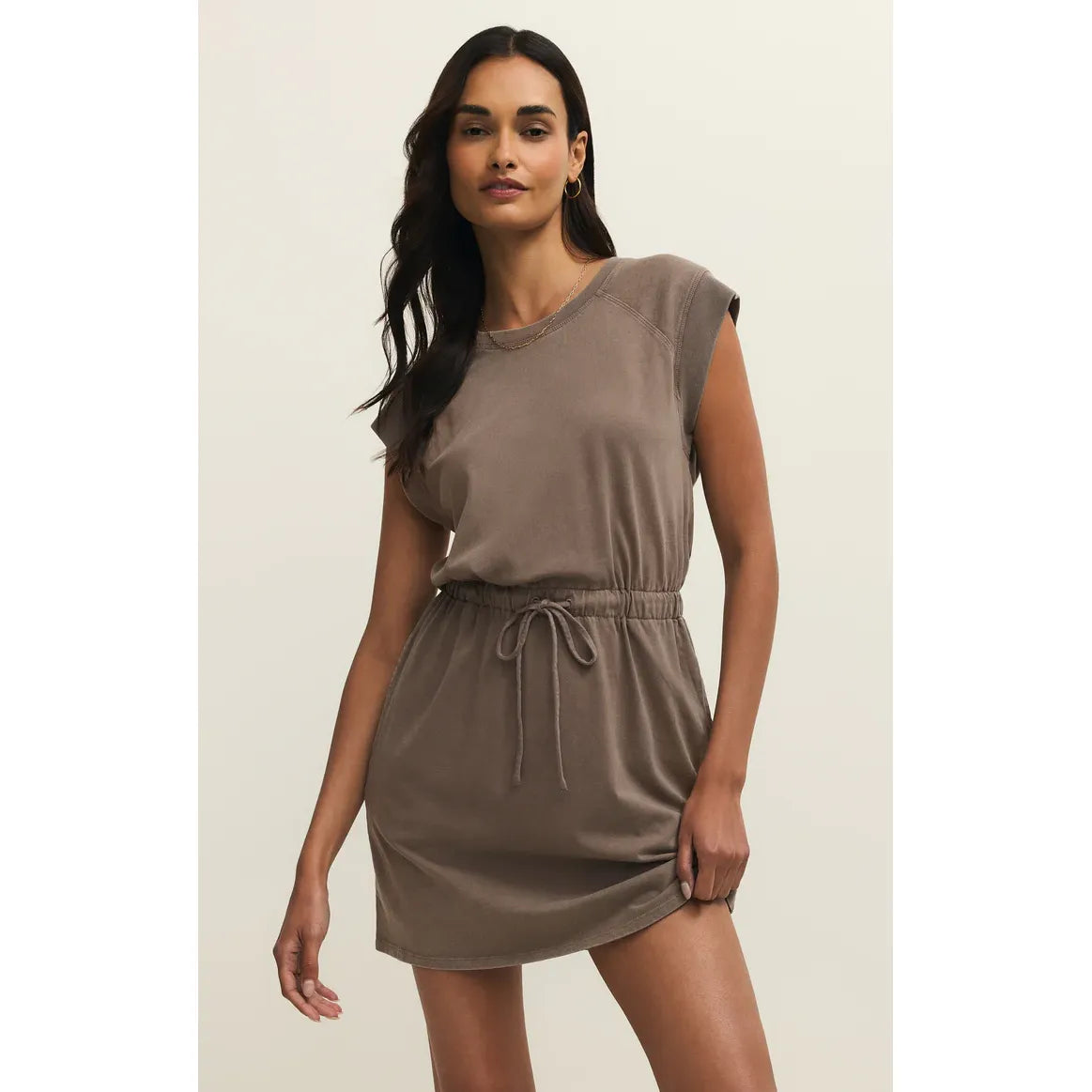 Model wearing Z Supply Kalani Mini Dress in taupe cotton jersey with elastic waist, drawstring, mini length.