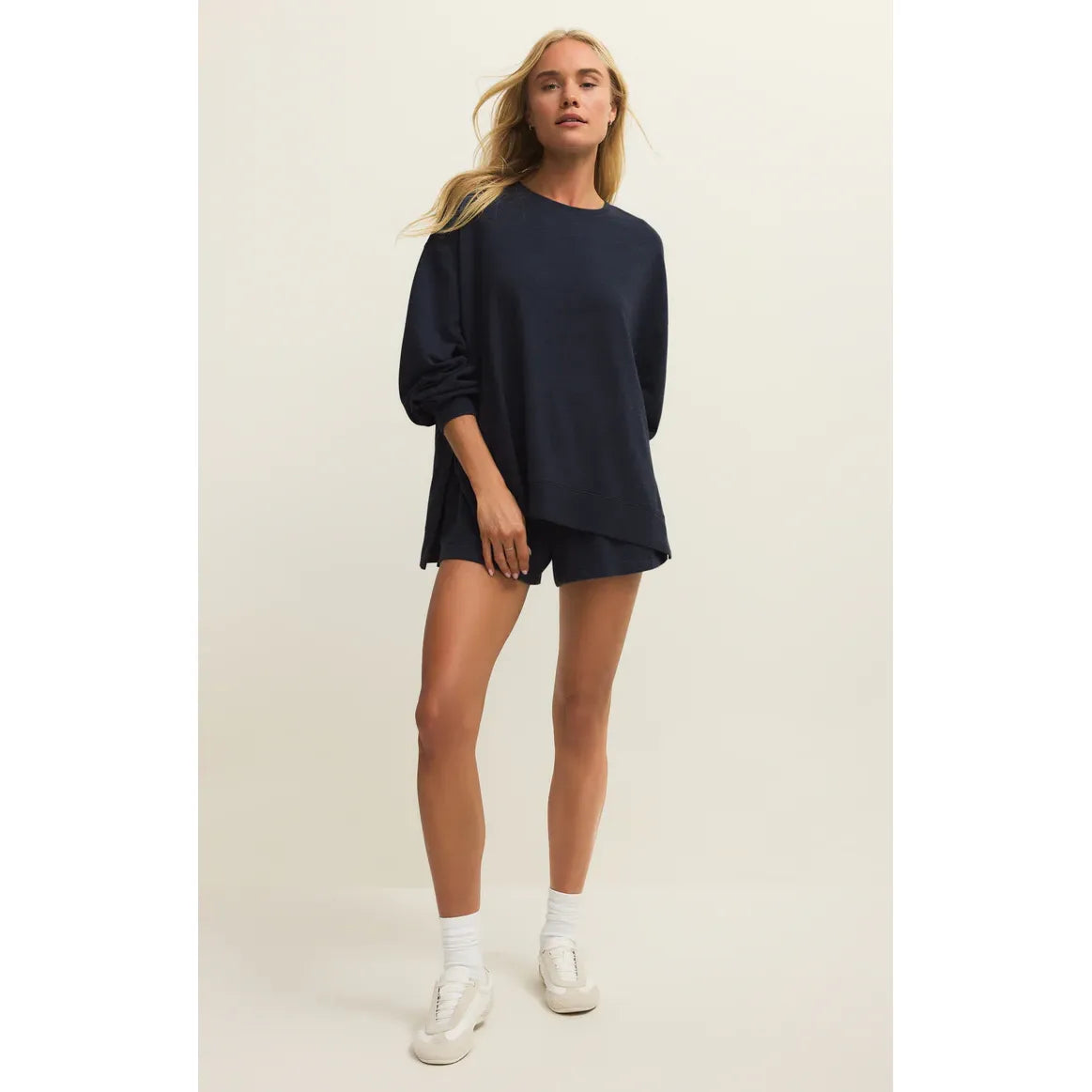 Woman wearing navy Z Supply Modern Weekender Sweatshirt with relaxed fit crewneck, paired with shorts.