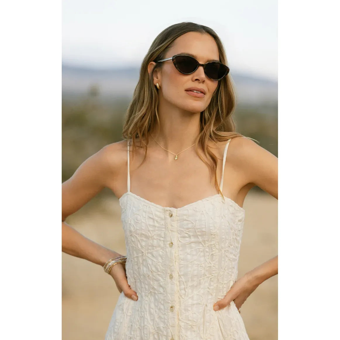 Woman wearing Z Supply Nouveau Sunglasses, mid-sized, sleek metal cat-eye frame with polarized lenses.