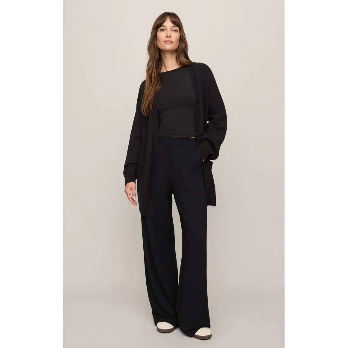 Female model in black Z Supply Sanborn Cardigan with ribbed trim and oversized patch pockets, paired with wide-leg black pants.