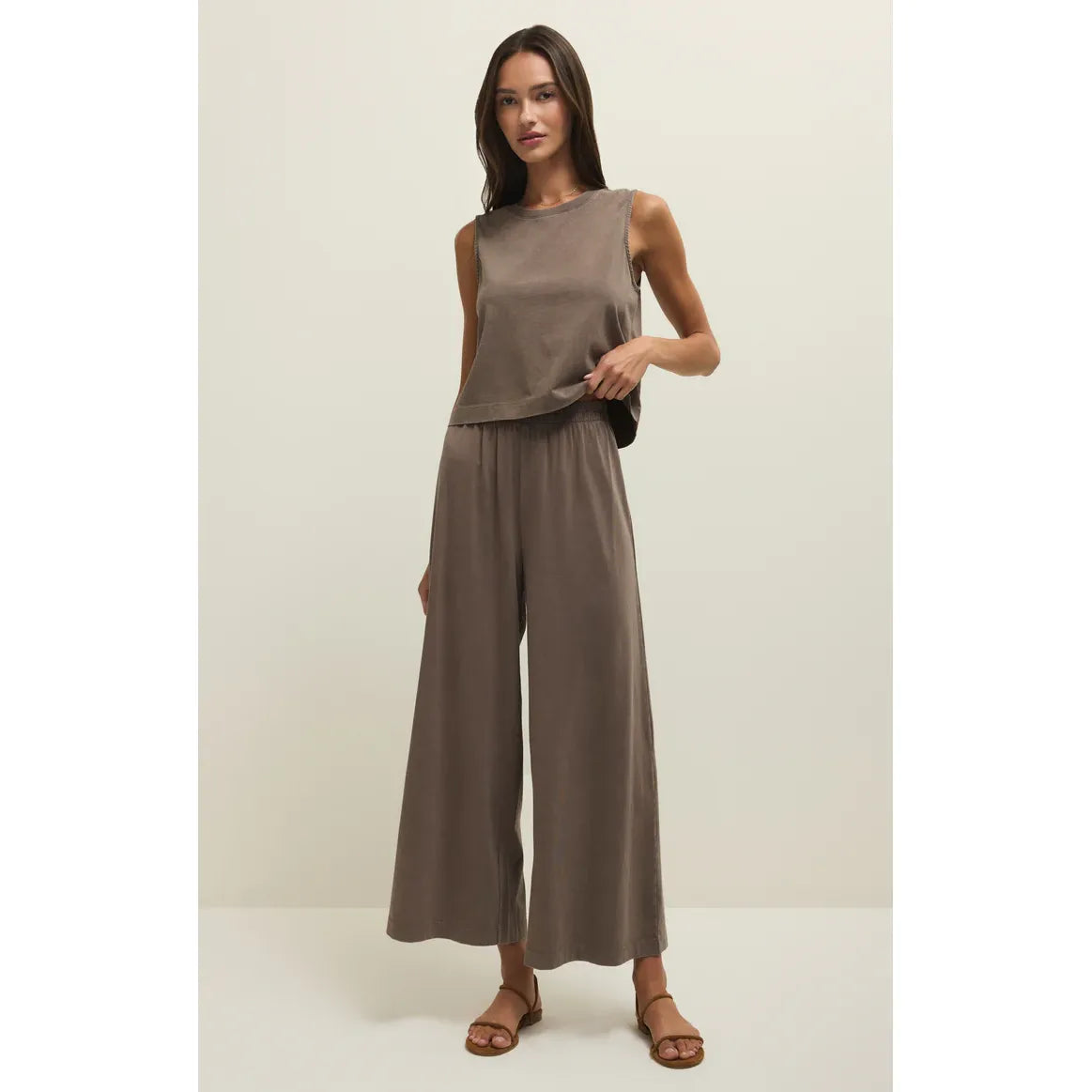 Model wears taupe Z Supply Scout Jersey Flare Pant set with high-rise, wide-leg cotton jersey pants and sleeveless top.
