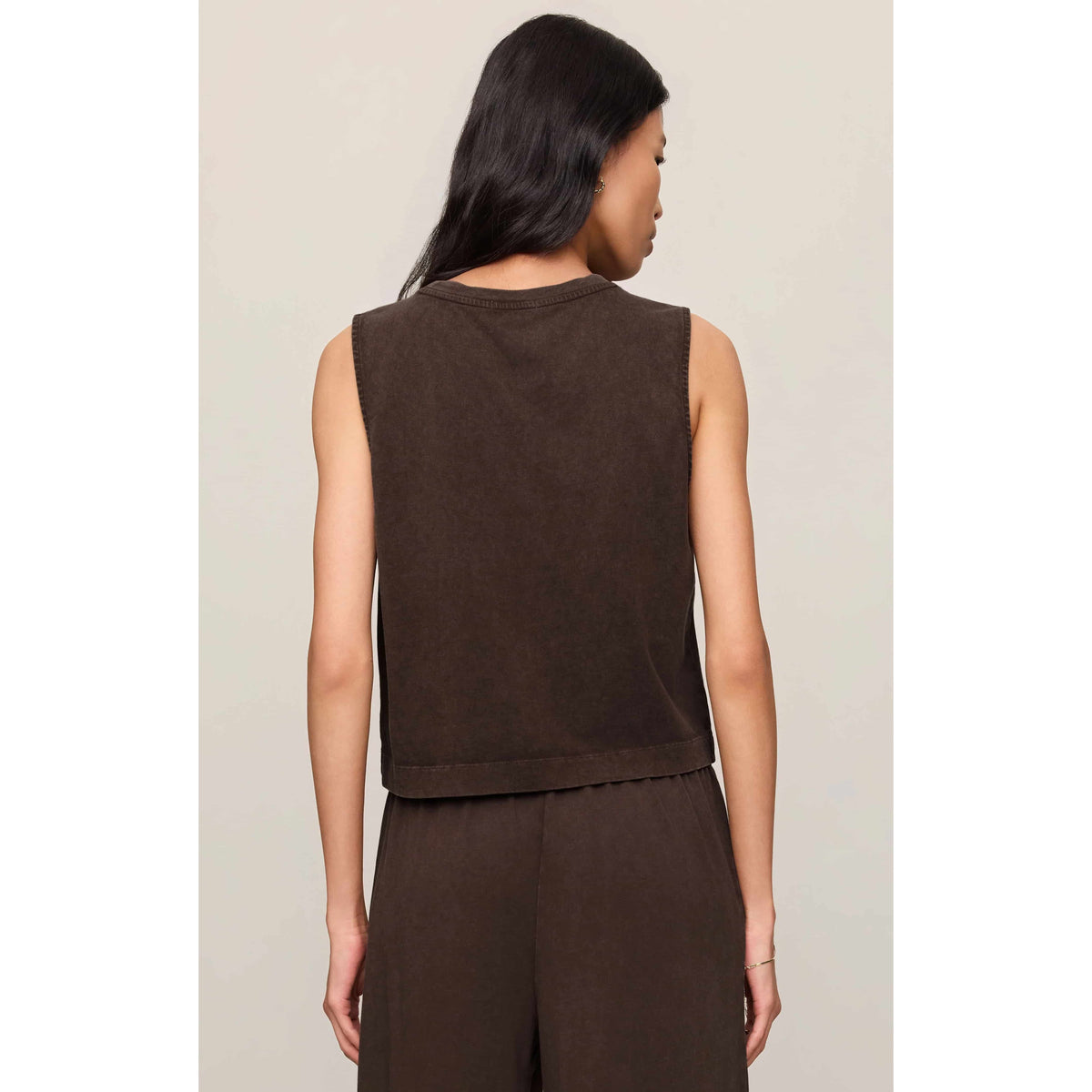 Back view of a model wearing a brown Z Supply Sloane Muscle Jersey Tank, sleeveless crew-neck with relaxed fit.