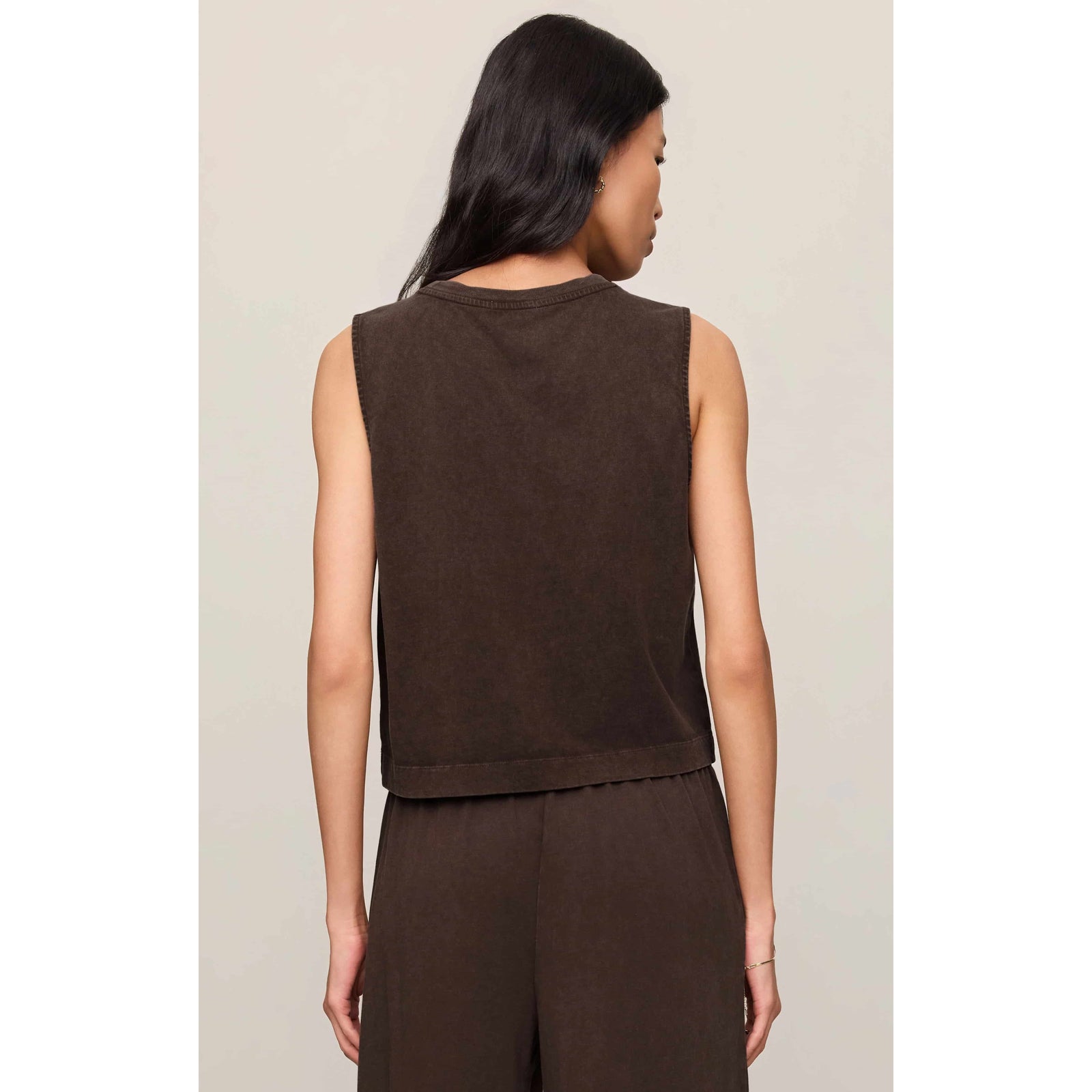 Back view of a model wearing a brown Z Supply Sloane Muscle Jersey Tank, sleeveless crew-neck with relaxed fit.