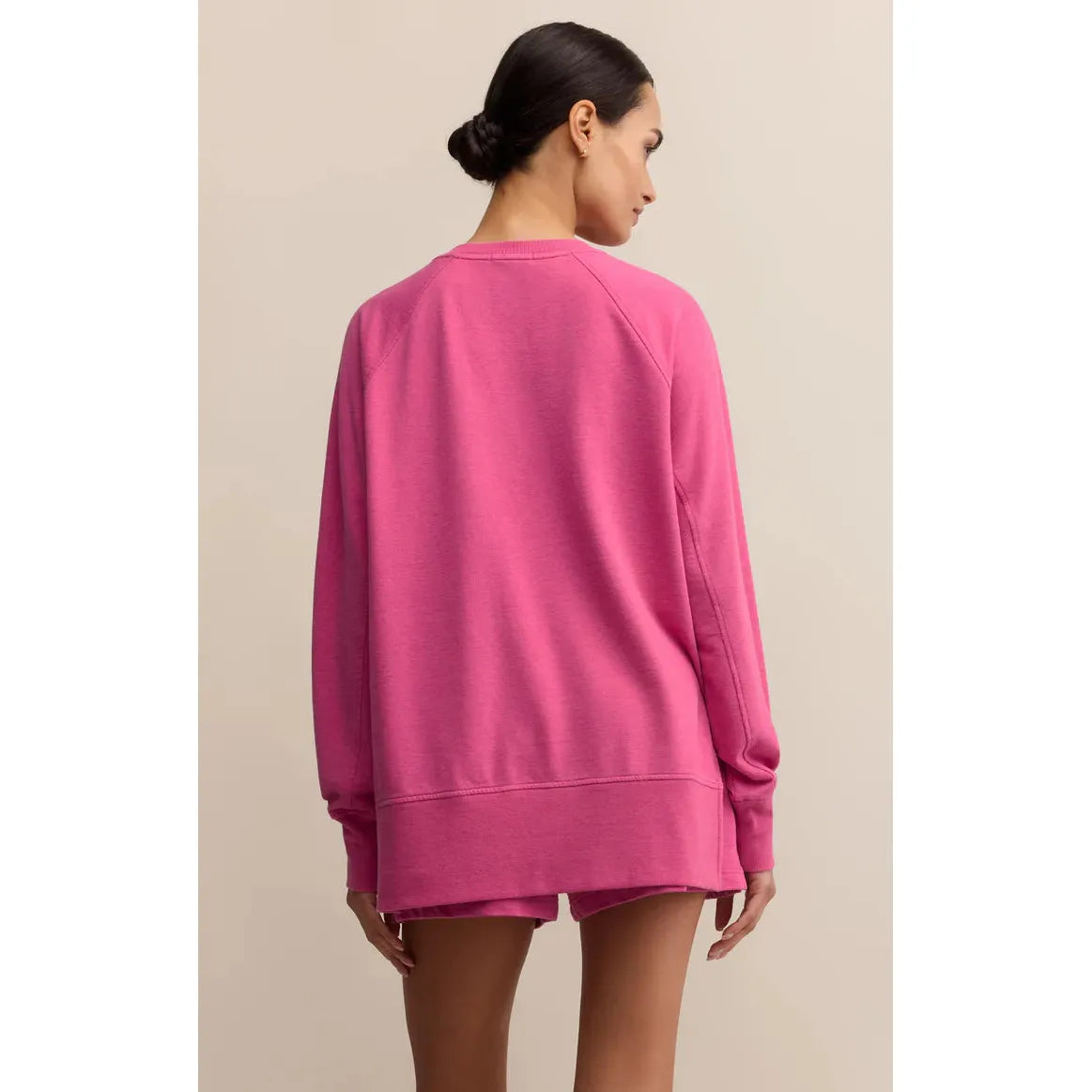 Back view of pink oversized Z Supply Modern V-Neck Weekender Top, long sleeve with hi-low hem.